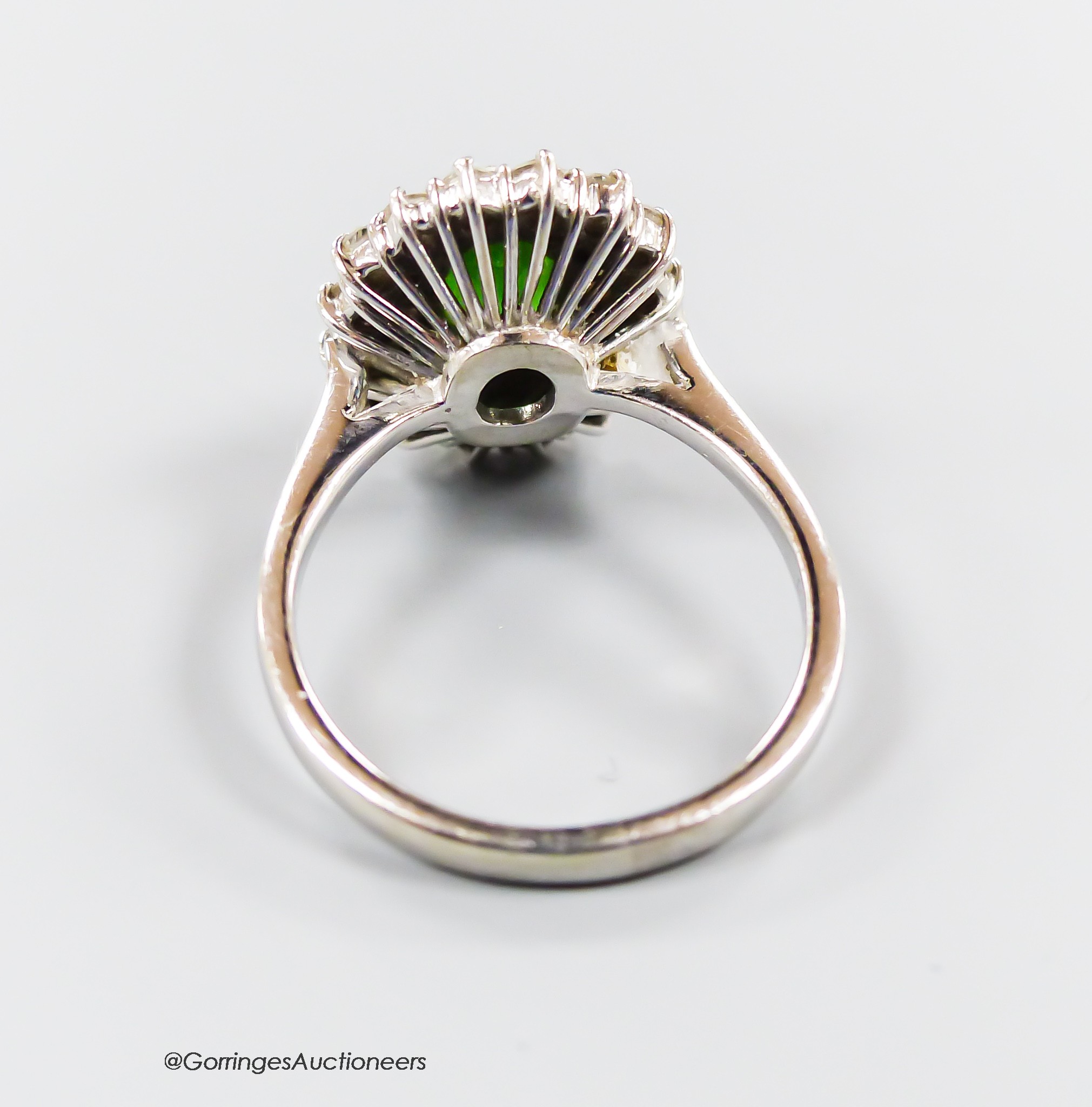 A modern 18ct white gold, green garnet and diamond set oval cluster ring, size N, gross weight 5.3 grams.